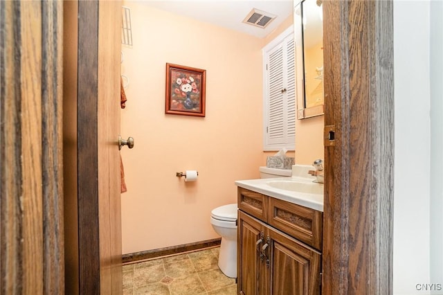 bathroom with baseboards, visible vents, vanity, and toilet