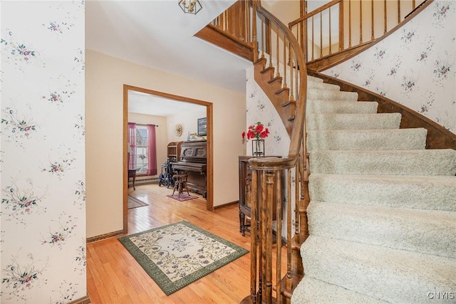 stairs with baseboards, hardwood / wood-style floors, and wallpapered walls