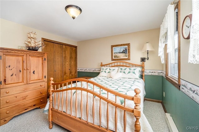 bedroom with light carpet, a closet, and a baseboard radiator