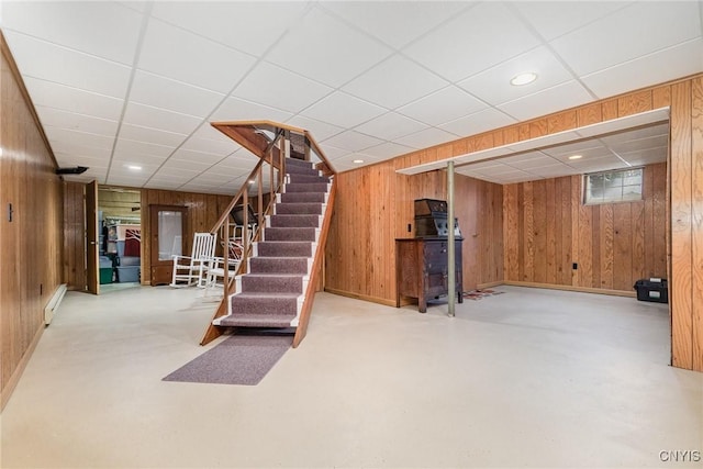 finished basement featuring stairway, recessed lighting, a paneled ceiling, and wooden walls