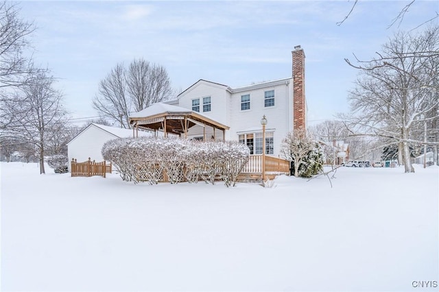 snow covered house featuring a deck, a chimney, and a gazebo