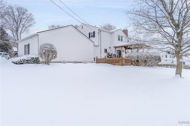 view of snowy exterior featuring a chimney