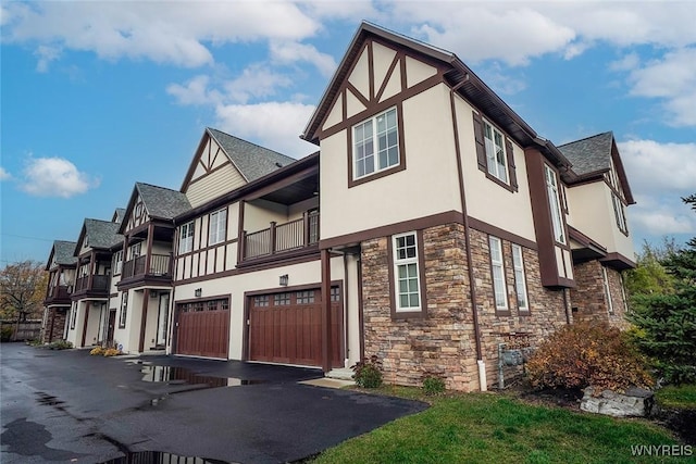 view of property exterior with stone siding, stucco siding, an attached garage, and driveway