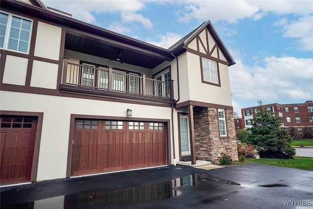 view of front facade featuring stucco siding, stone siding, a balcony, and an attached garage