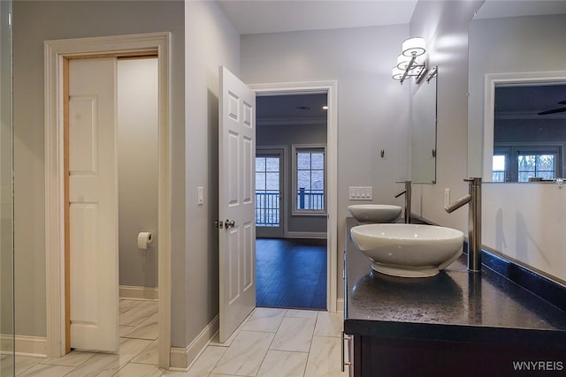 bathroom featuring double vanity, a healthy amount of sunlight, baseboards, and a sink