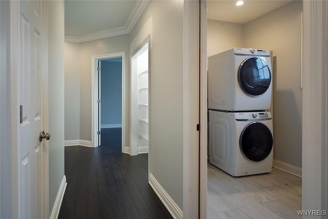 washroom with laundry area, stacked washing maching and dryer, baseboards, and ornamental molding