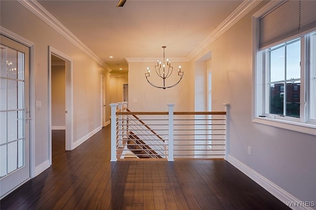 hall featuring hardwood / wood-style floors, baseboards, an inviting chandelier, crown molding, and an upstairs landing