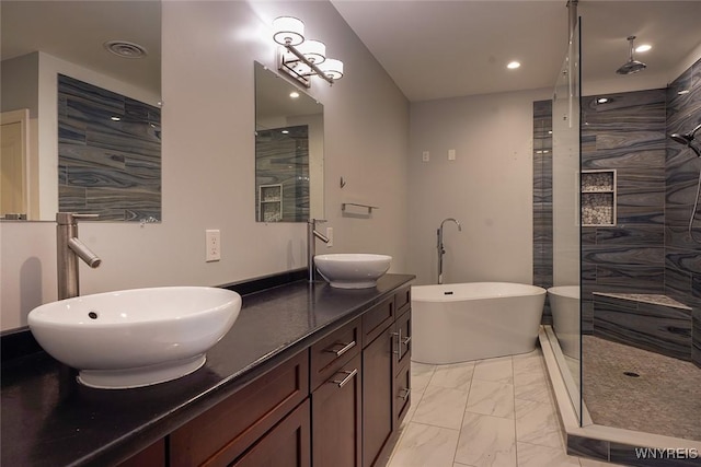 full bathroom featuring a sink, a freestanding tub, marble finish floor, and double vanity