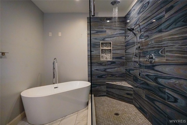 full bathroom with tiled shower and a freestanding bath