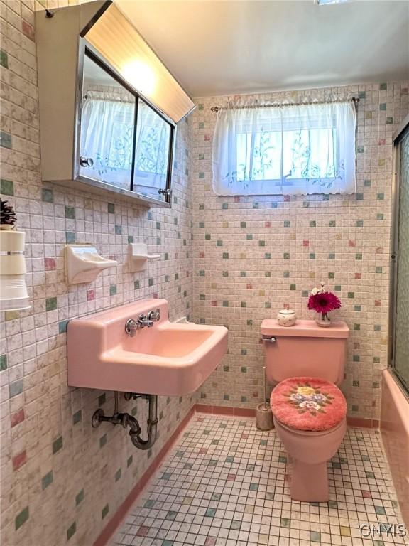 bathroom featuring shower / bath combination with glass door, tile patterned flooring, and toilet