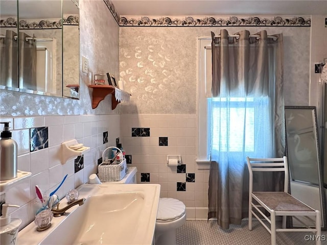 bathroom with toilet, a sink, tile walls, a shower, and tile patterned floors