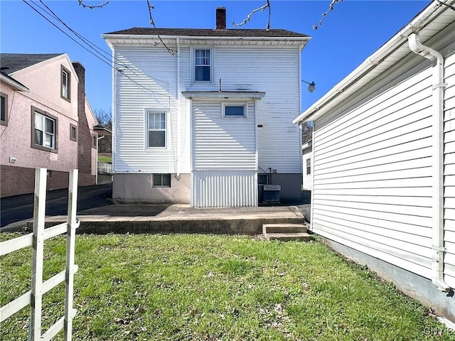 rear view of house featuring a patio area, a chimney, central AC, and a yard