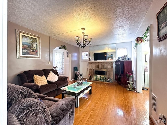 living room with plenty of natural light, a fireplace, arched walkways, and light wood finished floors