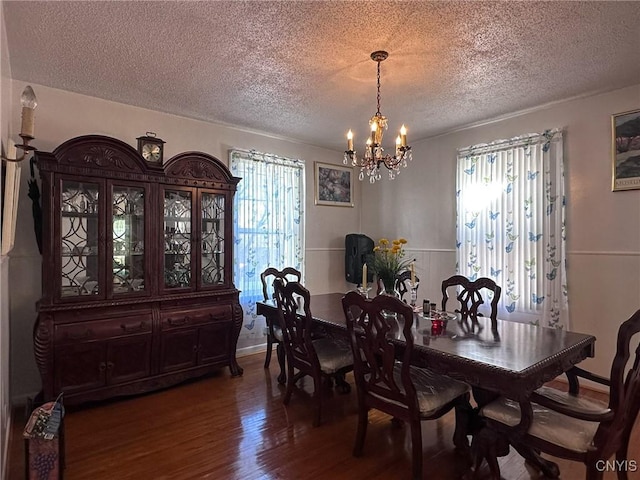 dining space featuring a notable chandelier, a textured ceiling, and wood finished floors