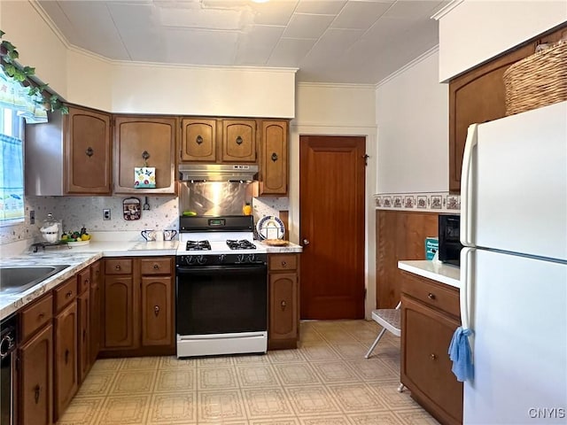 kitchen featuring light countertops, freestanding refrigerator, gas stove, dishwasher, and under cabinet range hood