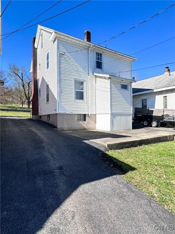 rear view of property with a chimney and aphalt driveway