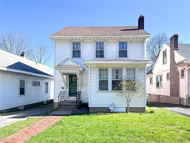 american foursquare style home with a shingled roof, a chimney, and a front yard