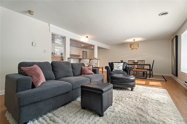 living area with light wood-style flooring, visible vents, and baseboards