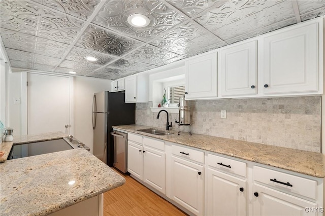 kitchen with an ornate ceiling, tasteful backsplash, stainless steel dishwasher, a sink, and light wood-type flooring