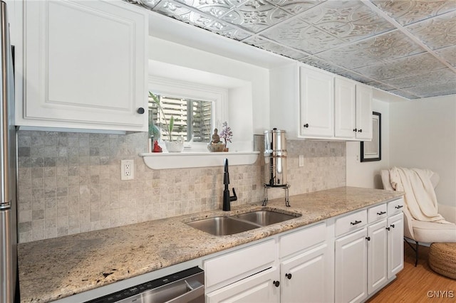 kitchen featuring an ornate ceiling, a sink, light wood-style floors, white cabinetry, and backsplash