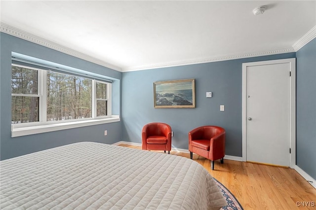 bedroom with ornamental molding, wood finished floors, and baseboards