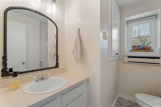 half bathroom with baseboards, a wall mounted air conditioner, vanity, and toilet