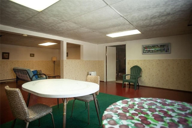 interior space with a wainscoted wall, a drop ceiling, wood finished floors, and wallpapered walls