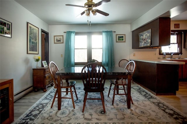 dining space with a ceiling fan, baseboard heating, and wood finished floors