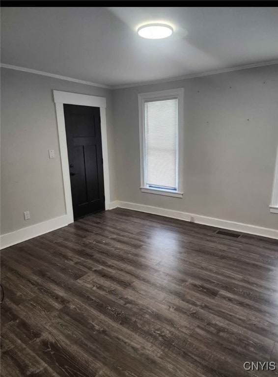 spare room with baseboards, visible vents, dark wood-style flooring, and crown molding