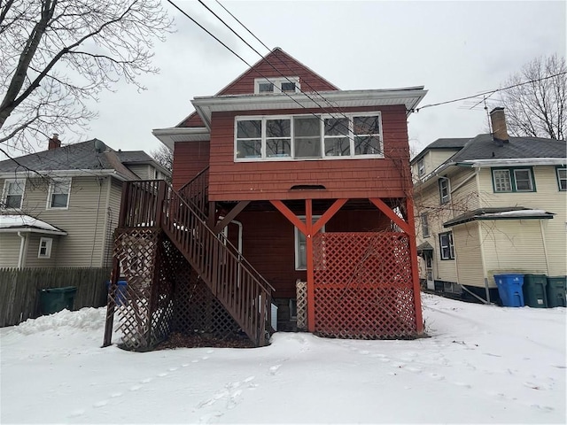 snow covered back of property with stairway and fence