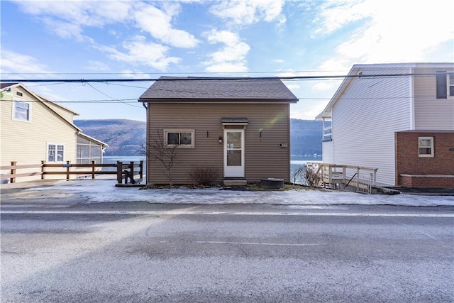 view of front of house featuring entry steps, roof with shingles, fence, and a mountain view