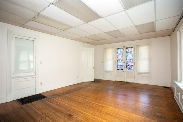 spare room with a paneled ceiling, wood-type flooring, and visible vents