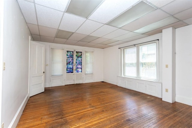 spare room with a paneled ceiling, hardwood / wood-style flooring, baseboards, and french doors