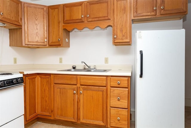 kitchen featuring white appliances, brown cabinetry, and a sink