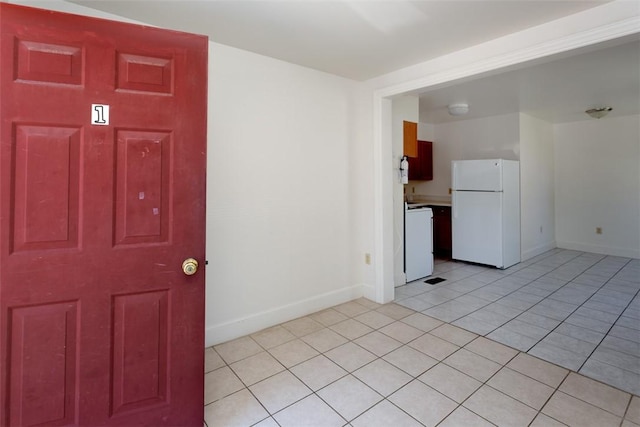 unfurnished room featuring washer / dryer, baseboards, and light tile patterned flooring