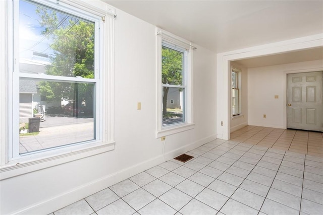 spare room featuring light tile patterned floors, plenty of natural light, and visible vents