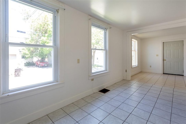 empty room with visible vents, plenty of natural light, and light tile patterned floors