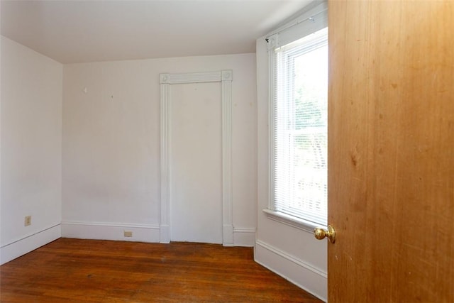 spare room featuring baseboards and wood finished floors