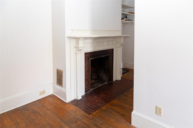 details with a fireplace with flush hearth, visible vents, and wood finished floors