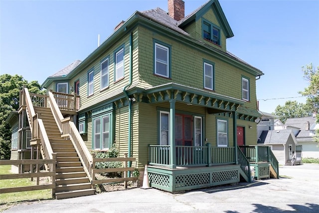 view of front of home with a garage, a chimney, stairway, and a porch