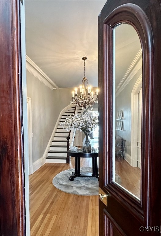 foyer featuring arched walkways, wood finished floors, stairs, and crown molding