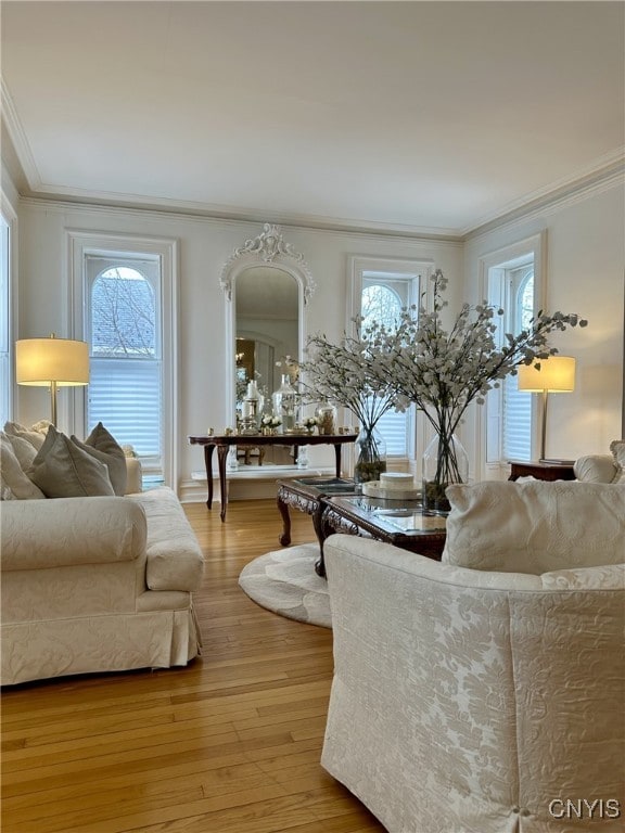 living room with crown molding, a healthy amount of sunlight, and light wood-style floors