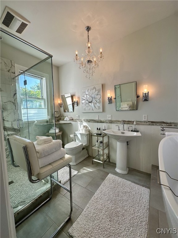 bathroom with a wainscoted wall, visible vents, toilet, a bathing tub, and a shower stall