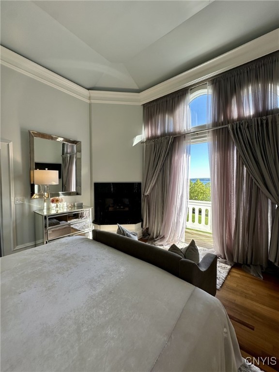 bedroom with lofted ceiling, ornamental molding, and wood finished floors