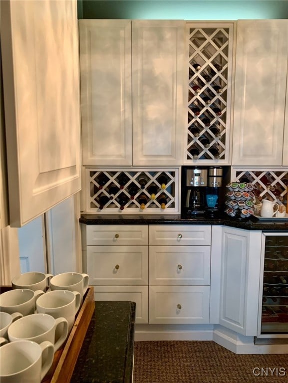 kitchen featuring dark stone counters, wine cooler, white cabinetry, and tasteful backsplash