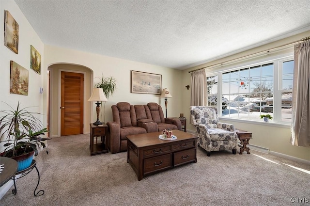 living area with arched walkways, a textured ceiling, baseboards, and light colored carpet