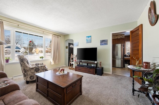 living room with a textured ceiling, arched walkways, a baseboard radiator, light carpet, and baseboards