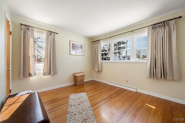 interior space with baseboards, a baseboard heating unit, and wood finished floors