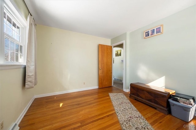 bedroom with baseboard heating, wood finished floors, and baseboards