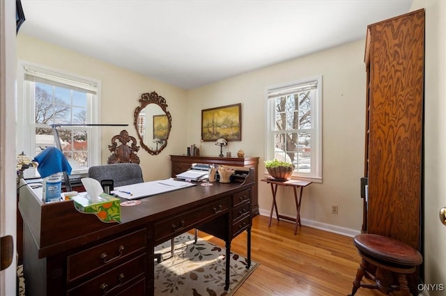 office space with light wood-type flooring, a wealth of natural light, and baseboards